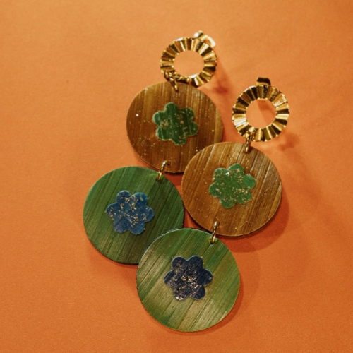 Boucle d'oreille en disque de trois rangés de couleurs verts bois et or et un dessin de fleur au milieu